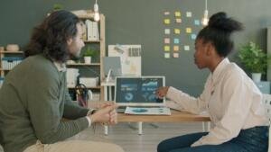 Marketing team discussing projects and data on a laptop, illustrative